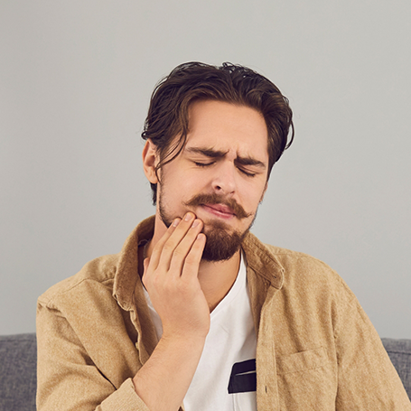 Man holding the side of his jaw in pain